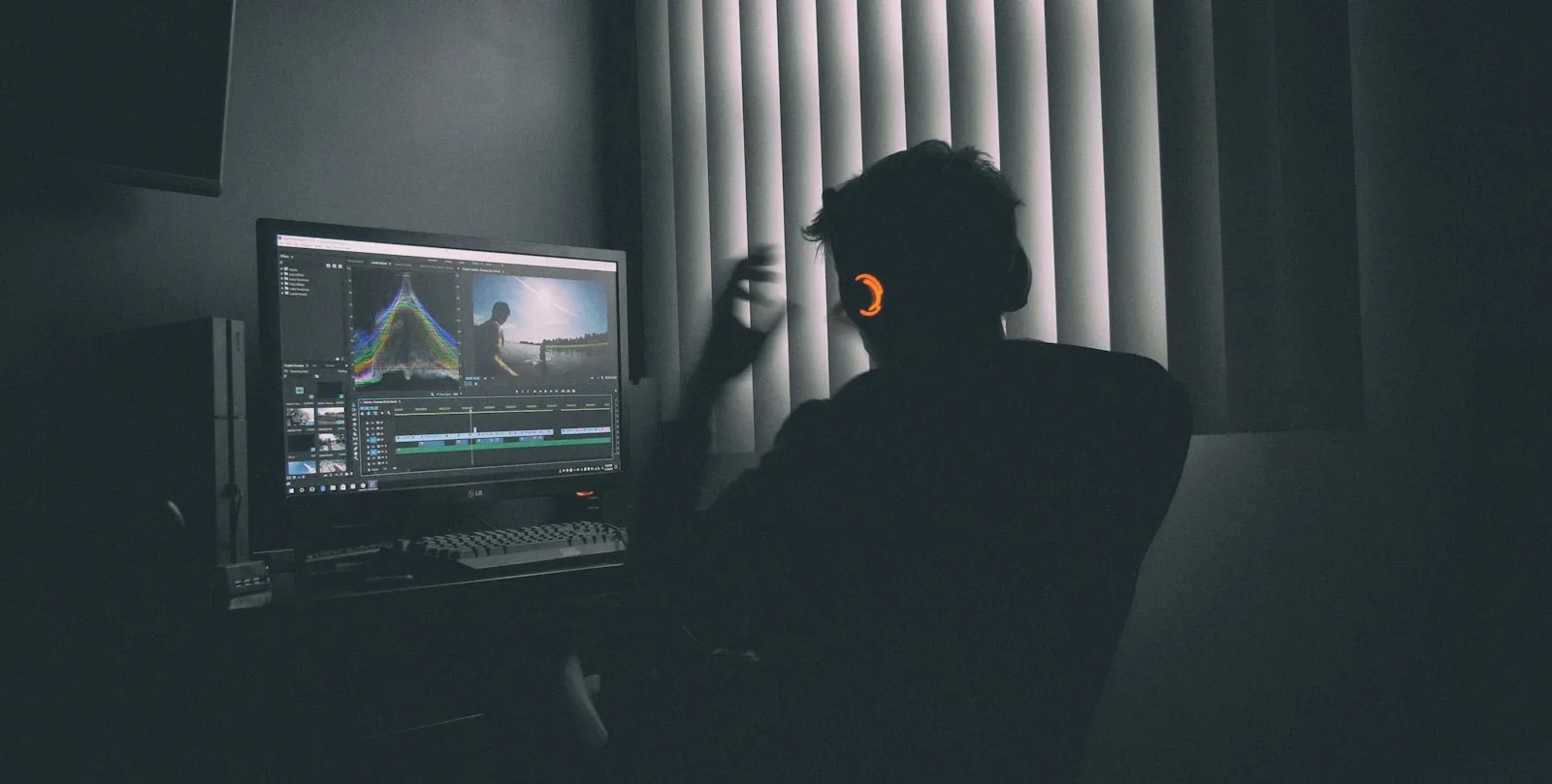 Silhouette of a person editing video at a workstation