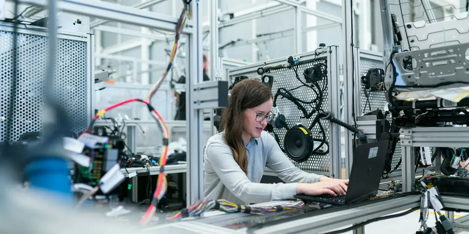 An engineer working at a laptop beside factory automation equipment