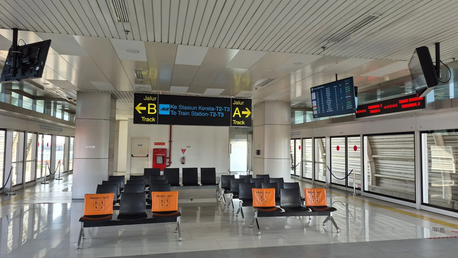 An empty airport terminal waiting area with flight-information displays